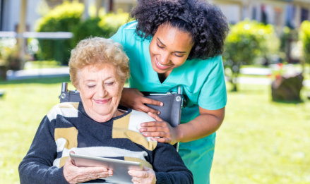 senior woman and caregiver looking at tablet