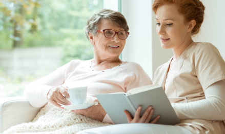 senior woman and caregiver reading a book