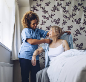 caregiver assisting senior woman put on clothes