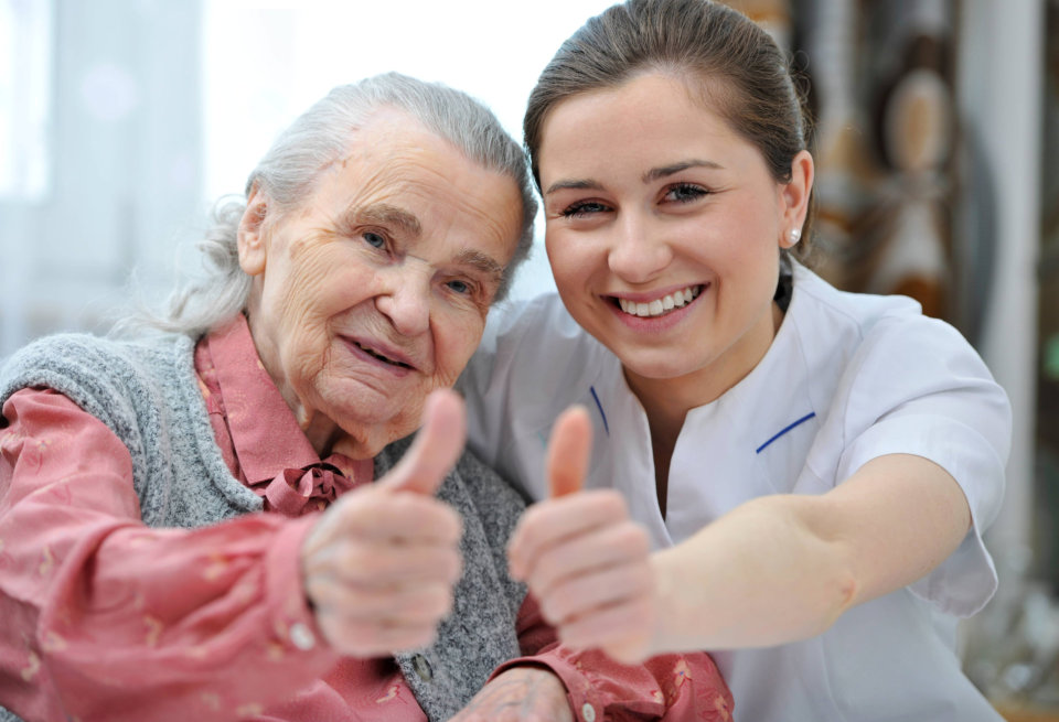 senior woman and caregiver giving thumbs up