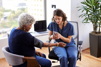 caregiver checking senior woman's blood pressure
