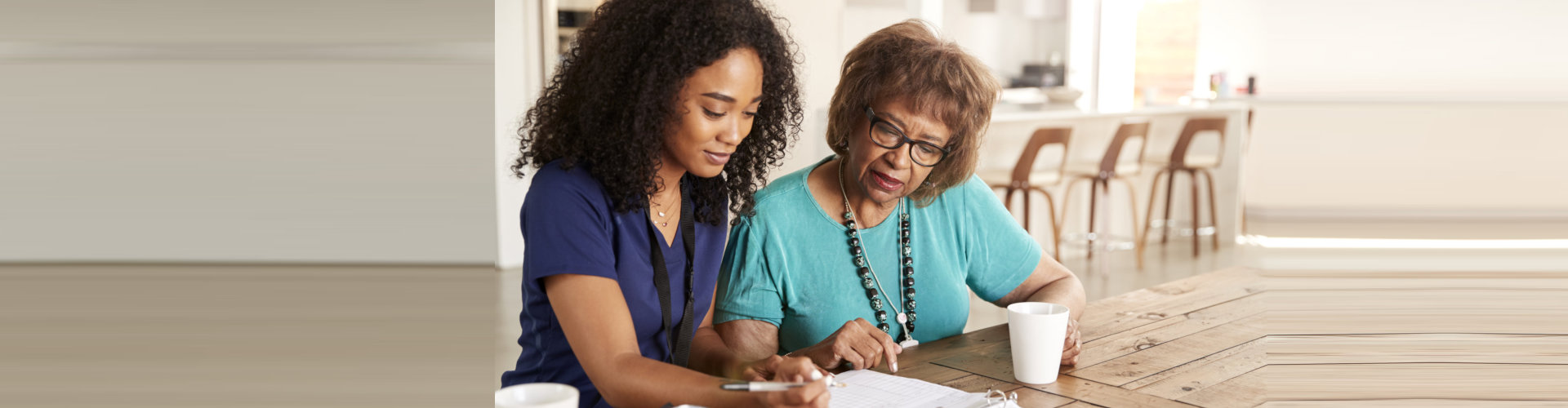caregiver helping senior woman sign papers